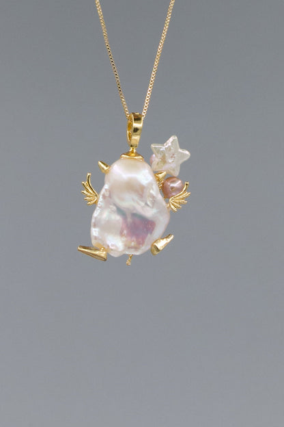 Gold pendant with a large baroque pearl and smaller stones on a gray background