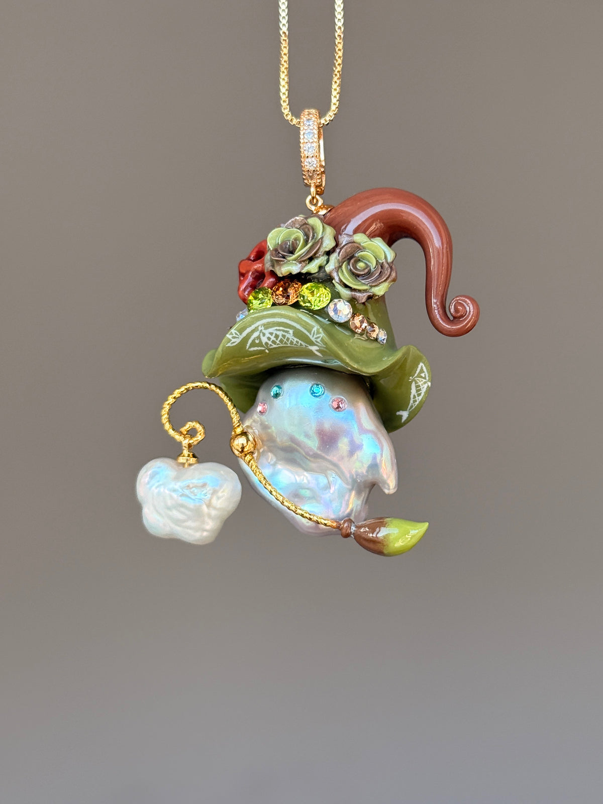 [PIECE07] Bakery Sprite baroque pearl necklace with olive green pretzel-inspired hat, sculpted pretzel detail, floral accents, gold wand, and natural baroque pearl